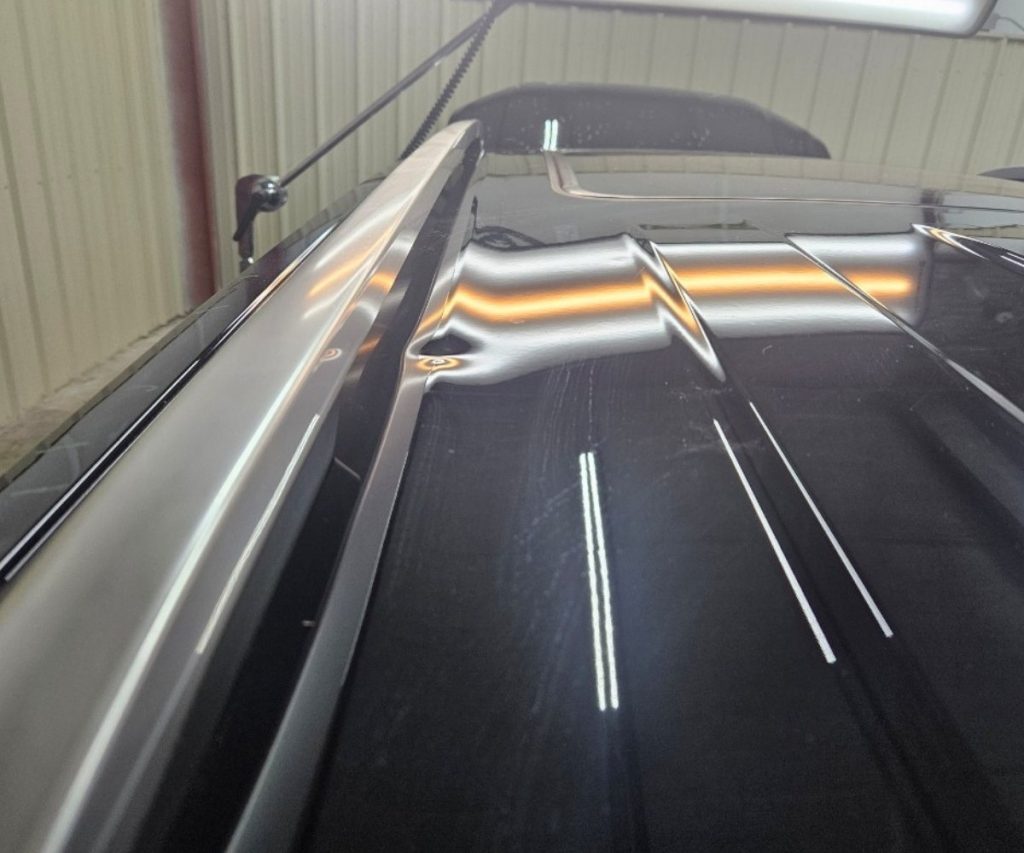 Dent in a car roof under a reflection line board before paintless dent repair