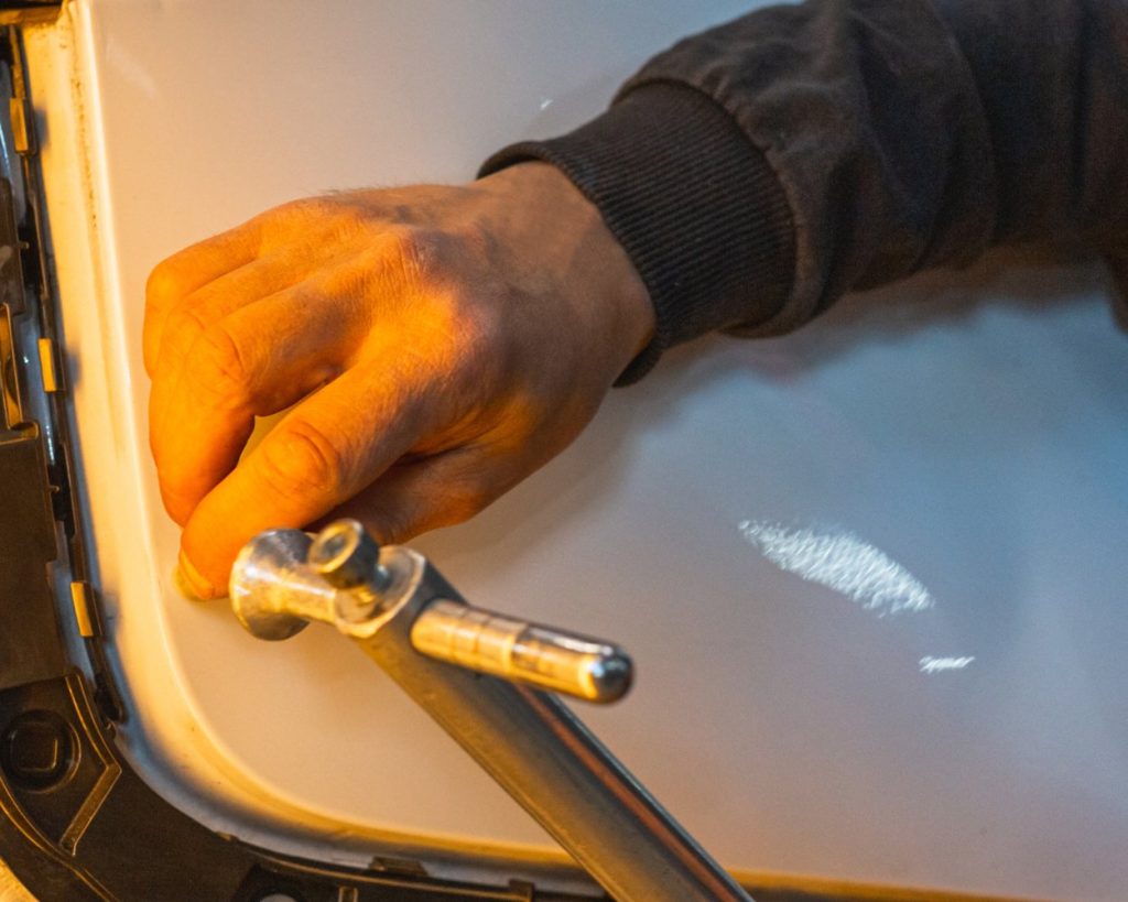 Technician working a dent out of a white car door